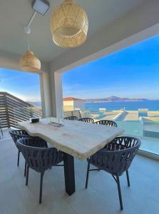 a dining room table with chairs and a view of the ocean at Βίλα -Θαλασσινή αύρα, 500μέτρα από την θάλασσα in Áyios Andónios