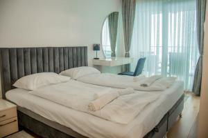 a large bed with white sheets and a chair in a bedroom at My River Walk apartment - Ilidza in Sarajevo