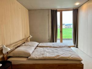 ein Schlafzimmer mit einem großen Bett und einem großen Fenster in der Unterkunft Architektenhaus RHaa mit Terrassen in Altach