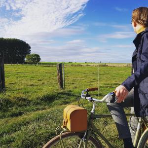 Una mujer está montando una bicicleta en un campo en Guesthouse De Wissen en Dilsen-Stokkem