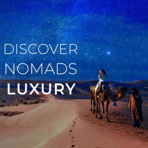 Una mujer montando un camello en el desierto por la noche en Nomads Luxury Camp Merzouga en Hassilabied