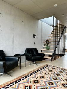 een woonkamer met twee zwarte stoelen en een tapijt bij Architektenhaus RHaa mit Terrassen in Altach