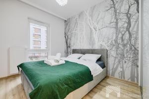 a bedroom with a bed with a green blanket at Ilumino Prestige by LookAp - Centrum in Łódź
