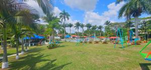 un parque con parque infantil y palmeras en Cabañas Cafeteras Cerritos, en Pereira