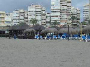 eine Gruppe von Stühlen und Sonnenschirmen am Strand in der Unterkunft Apartamento Buen Dia airport Malaga- playa-Torremolinos in Málaga