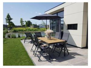 a wooden table and chairs with an umbrella on a patio at Holiday home Chalet 79 in Olburgen