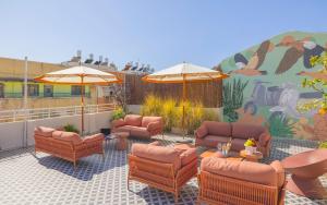 eine Terrasse mit Stühlen, Tischen und Sonnenschirmen in der Unterkunft Albi Florentin in Tel Aviv