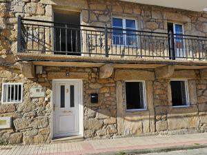 - un bâtiment en pierre avec une porte blanche et un balcon dans l'établissement Carmen House - Laxe - Costa da Morte, à Laxe