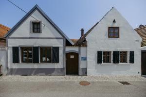 a white house with a brown door on a street at Streckhof Stiefelgasse 3 in Purbach am Neusiedlersee