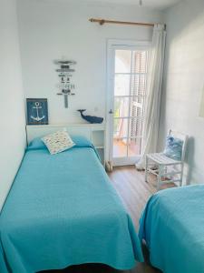 una camera con un letto blu e una sedia di Precioso apartamento piscinas Cala en Porter a Cala'n Porter