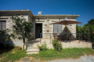 una casa con portico e ombrellone di Zouri Apartments a Kíssamos