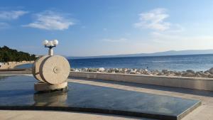 a stone bench next to the water with a beach at Rooms & Apartments Villa Anka in Tučepi