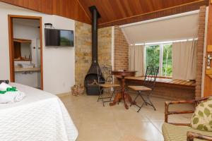 a bedroom with a bed and a fireplace in a room at Pousada das Bromélias in Ipiabas