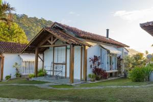 Casa blanca pequeña con techo de madera en Pousada das Bromélias en Ipiabas