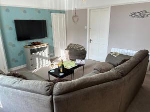 a living room with a couch and a television at 5 Beechcroft Cottage - Seahouses Northumberland in Seahouses