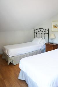 two beds in a room with white sheets at Casa Videira - Hotel rural cerca del mar in Bueu
