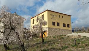 a building on top of a hill with a tree at Hostal Restaurant Mussons Vins in Poboleda