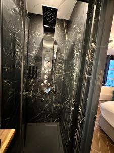 La salle de bains est pourvue d'une douche et d'un mur en marbre noir. dans l'établissement G Eighty Four, à Londres