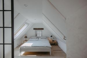 a white bedroom with a bed in the attic at Streckhof Stiefelgasse 3 in Purbach am Neusiedlersee