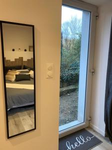 een spiegel in een kamer met een bed en een raam bij Maisonnette 2/4 personnes en bord de sevre in Cugand