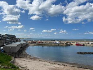 a view of a beach with a pier and the ocean at 5 Beechcroft Cottage - Seahouses Northumberland in Seahouses