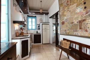 a kitchen with a white refrigerator and a bench in it at Historical Stone Manor-Upper floor in Hydra