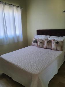 Un dormitorio con una cama blanca con almohadas y una ventana en Casa de Praia- Village Dunnas- Bal. Gaivota-SC en Balneário Gaivotas