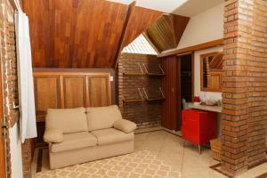 a living room with a chair and a kitchen at Pousada das Bromélias in Ipiabas