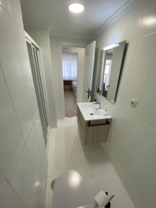 a white bathroom with a sink and a mirror at Espacioso Apartamento Familiar en Aranjuez - Confort, Tranquilidad y Netflix Incluido in Aranjuez