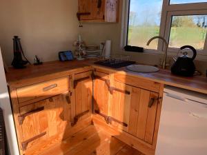eine Küche mit Holzschränken, einem Waschbecken und einem Fenster in der Unterkunft Red Sheds Cabin in Portarlington