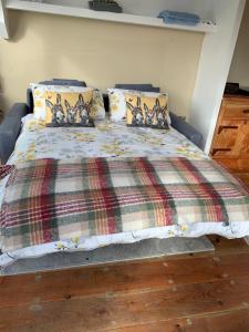 ein Bett mit einer karierten Decke und Kissen in der Unterkunft Red Sheds Cabin in Portarlington