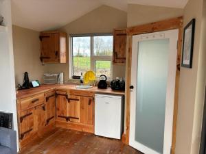 cocina con armarios de madera y nevera blanca en Red Sheds Cabin, en Portarlington