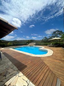 een groot zwembad met een houten terras en een blauwe bij Pousada Serra Morena in Serra do Cipo
