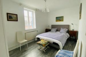 ein Schlafzimmer mit einem Bett und einem Stuhl und einem Fenster in der Unterkunft Gîte du Moulin - Appartement plein centre ville - spacieux 2p - 1er etage maison de pécheur à 100m de la plage in Le Crotoy