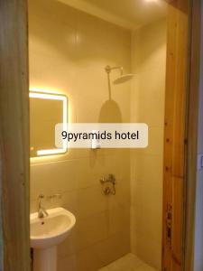 een badkamer met een wastafel, een toilet en een spiegel bij 9pyramids hotel in Caïro
