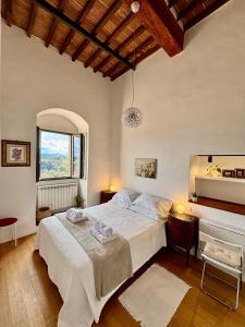 Un dormitorio con una gran cama blanca y una ventana en La Torre di Canonica, en Colle Val D'Elsa