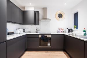 a kitchen with black cabinets and white counter tops at Dazzling & Modern 4bd - Nr Etihad - Parking -EV in Manchester