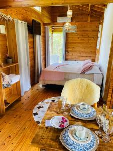 Un dormitorio con una cama y una mesa con platos de comida. en Cabana Refúgio - Pousada Colina dos Ventos, en Urubici