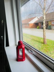 a red candle sitting on a window sill at 1 private room in Billund in Billund