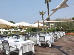 a row of tables and chairs with white tables and umbrellas at Hotel Caesius Thermae & Spa Resort in Bardolino