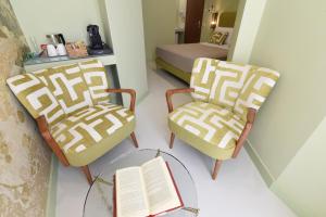 um quarto com duas cadeiras e uma mesa com um livro em Sorrento Rooms Deluxe em Sorrento