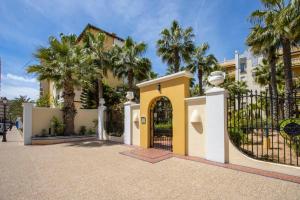 een huis met een poort en palmbomen bij Aldea del Mar Buganvilla Apartament in Torrevieja