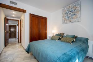 een slaapkamer met een groot bed met een blauw dekbed bij Aldea del Mar Buganvilla Apartament in Torrevieja