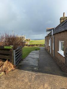 a sidewalk next to a house and a fence at Pentland view croft with a sea view in Melvich