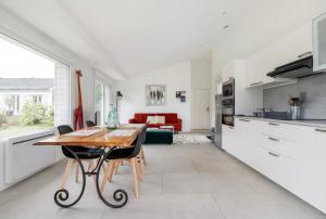 cocina y sala de estar con mesa de madera y sillas en Villa entourée de verdure avec parking privé, en Halluin