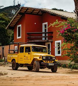 un camión amarillo estacionado frente a una casa roja en EcoPousada Pico do Jabre en Matureia