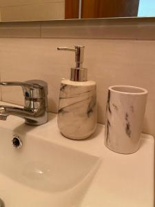 een wastafel in de badkamer met een zeepdispenser en een kopje bij Cávado Terrace Studio in Parada de Tibães