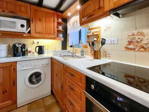 a kitchen with a washing machine and a sink at Hidden Cottage in Spark Bridge