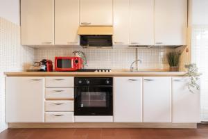 a kitchen with white cabinets and a red microwave at Big Deluxe apts Italian Style Lake&Terrace in Lecco
