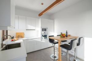 cocina con armarios blancos y mesa de madera en Finca Las Huellas - Moderno apartamento con vistas al mar y al volcán, en Los Llanos de Aridane